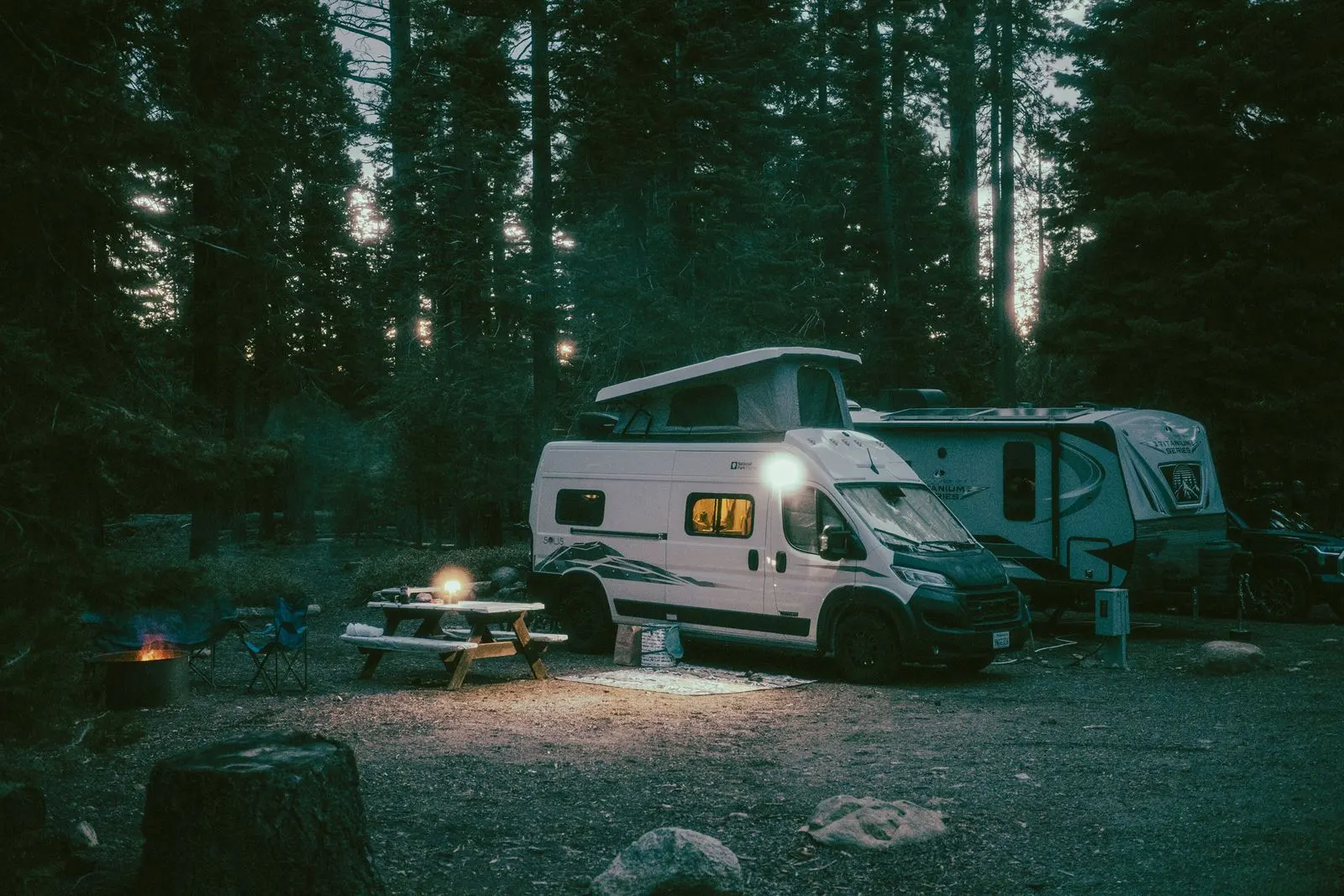 A campervan conversion parked at a woodland campsite at dusk