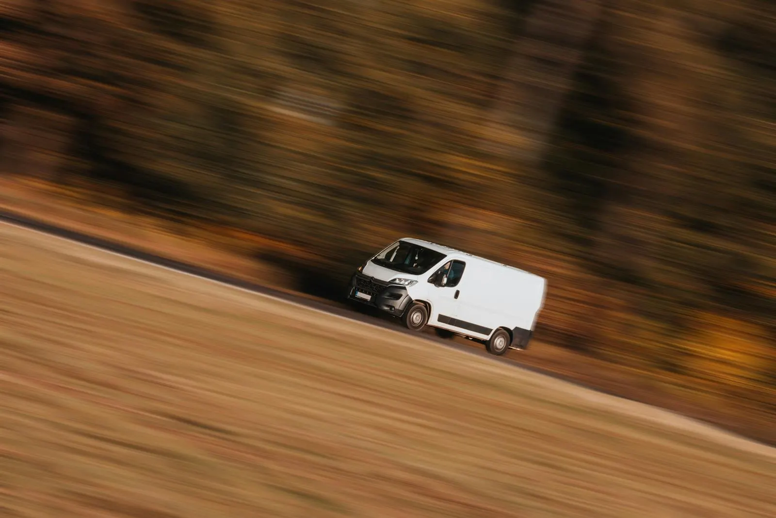 A white Citroen Relay van driving along a country road